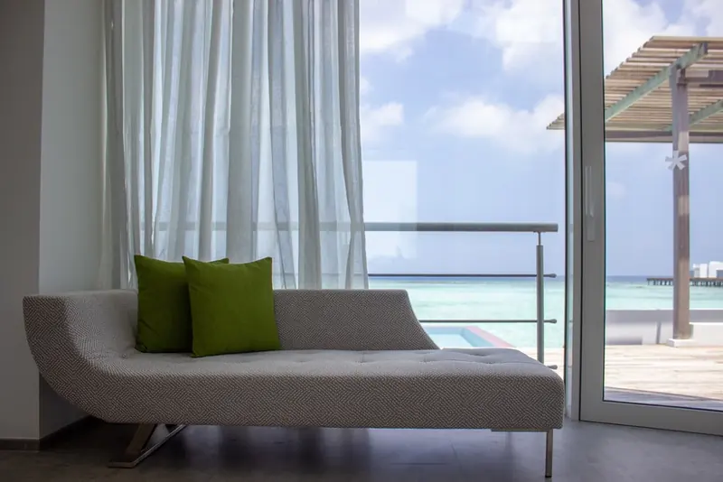 A daybed with two green cushions beside a bright window
